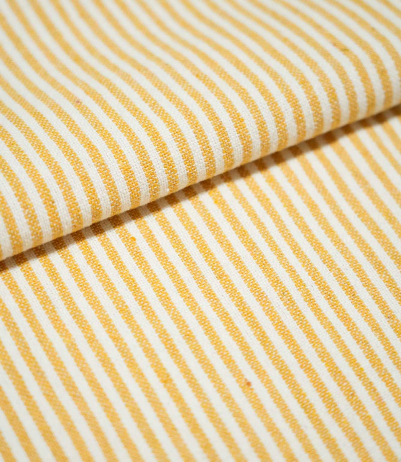 Folded Aldsworth Ticking Ochre fabric displaying its narrow ochre and off-white stripe pattern and detailed woven texture.