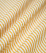 Aldsworth Ticking Ochre fabric arranged in soft, flowing folds, showing the narrow golden yellow ticking stripes and natural drape.