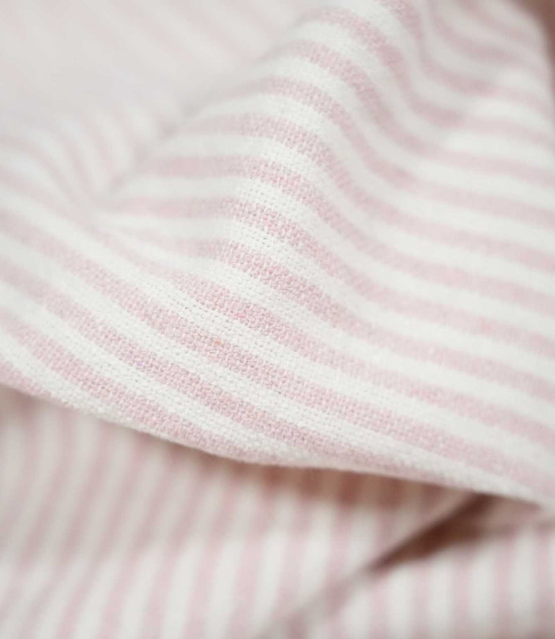 Close-up of Aldsworth Ticking Pink striped fabric draped in a soft fold, highlighting the delicate pink and white stripes and textured weave.
