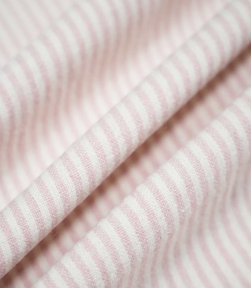 Aldsworth Ticking Pink fabric arranged in gentle folds, displaying its fine blush pink ticking stripes and softly textured woven finish.