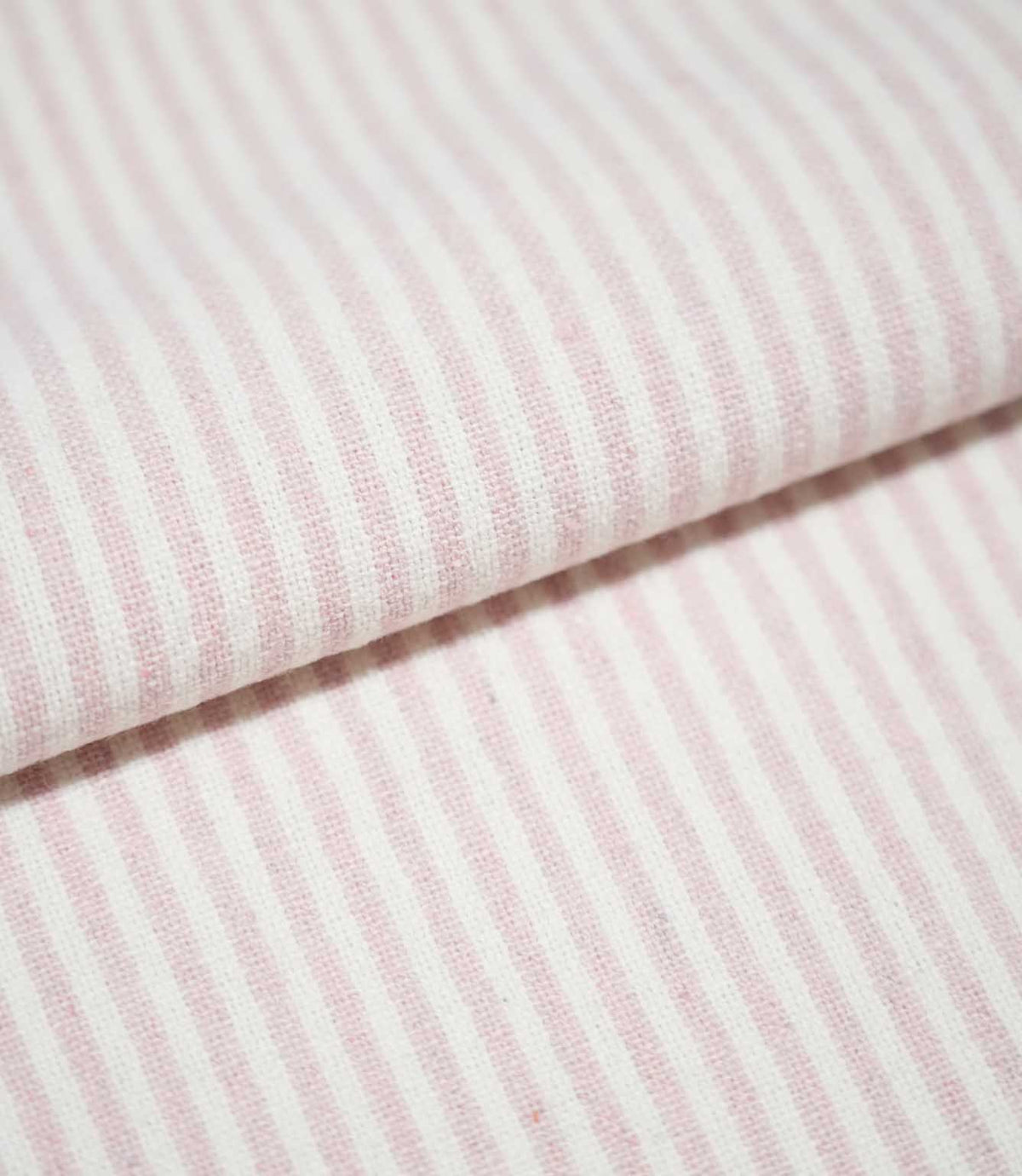 Folded Aldsworth Ticking Pink fabric showing the repeating narrow pink and off-white stripe pattern and detailed woven texture.