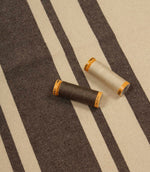 Brown striped furnishing fabric with natural tones, shown with coordinating thread reels to highlight colour matching.