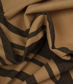 Softly draped black stripe fabric featuring bold and narrow stripes on a warm camel background.