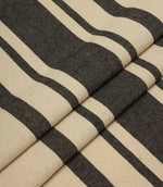 Folded striped upholstery fabric in cream and black tones with a soft drape and textured woven surface.