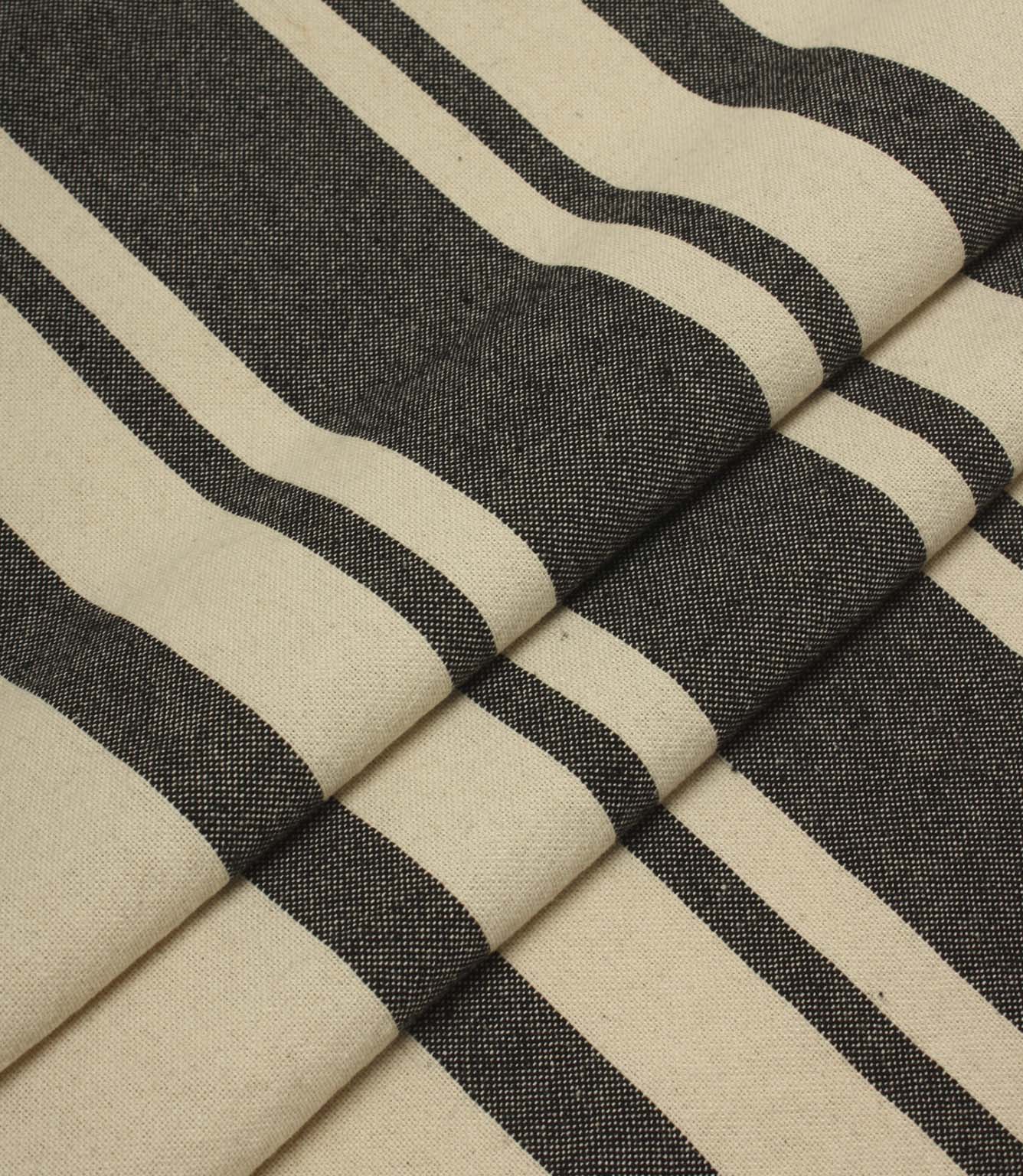 Folded striped upholstery fabric in cream and black tones with a soft drape and textured woven surface.