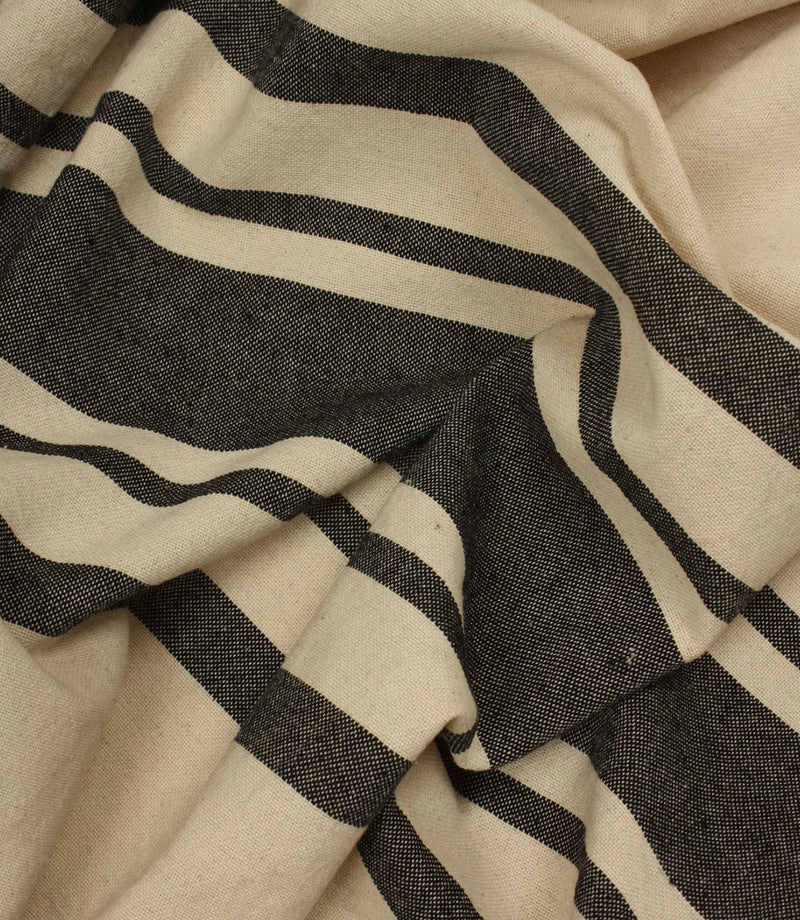 Softly gathered cream and black striped fabric showing bold stripe detailing and natural woven texture.