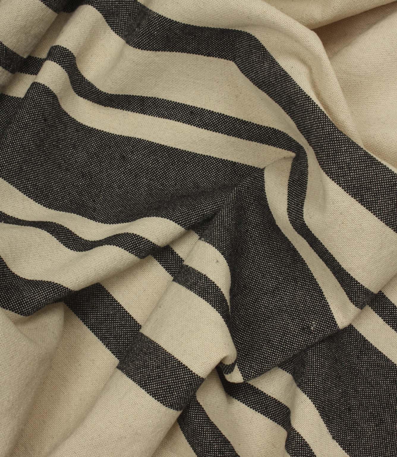 Softly gathered cream and black striped fabric showing bold stripe detailing and natural woven texture.