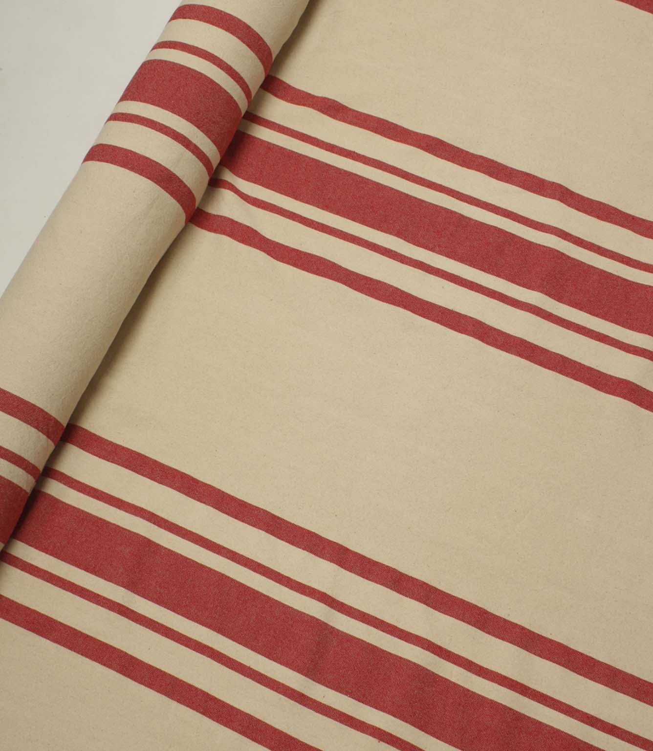 Rolled cream fabric with bold red stripe detailing displayed flat to show the full stripe repeat and pattern scale.