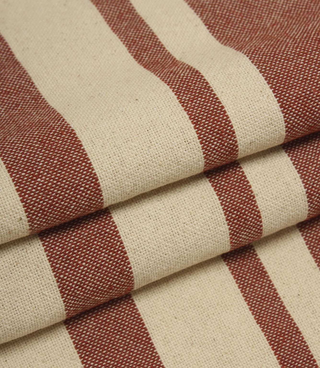 Detailed close-up of folded cream and terracotta striped fabric with textured weave and contrasting stripe design.