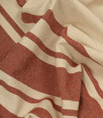 Gathered cream and terracotta striped fabric highlighting the soft drape and relaxed woven texture.
