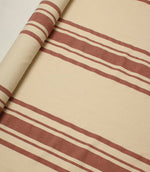 Rolled cream fabric with muted terracotta stripe detailing displayed flat to show the full stripe repeat and pattern scale.