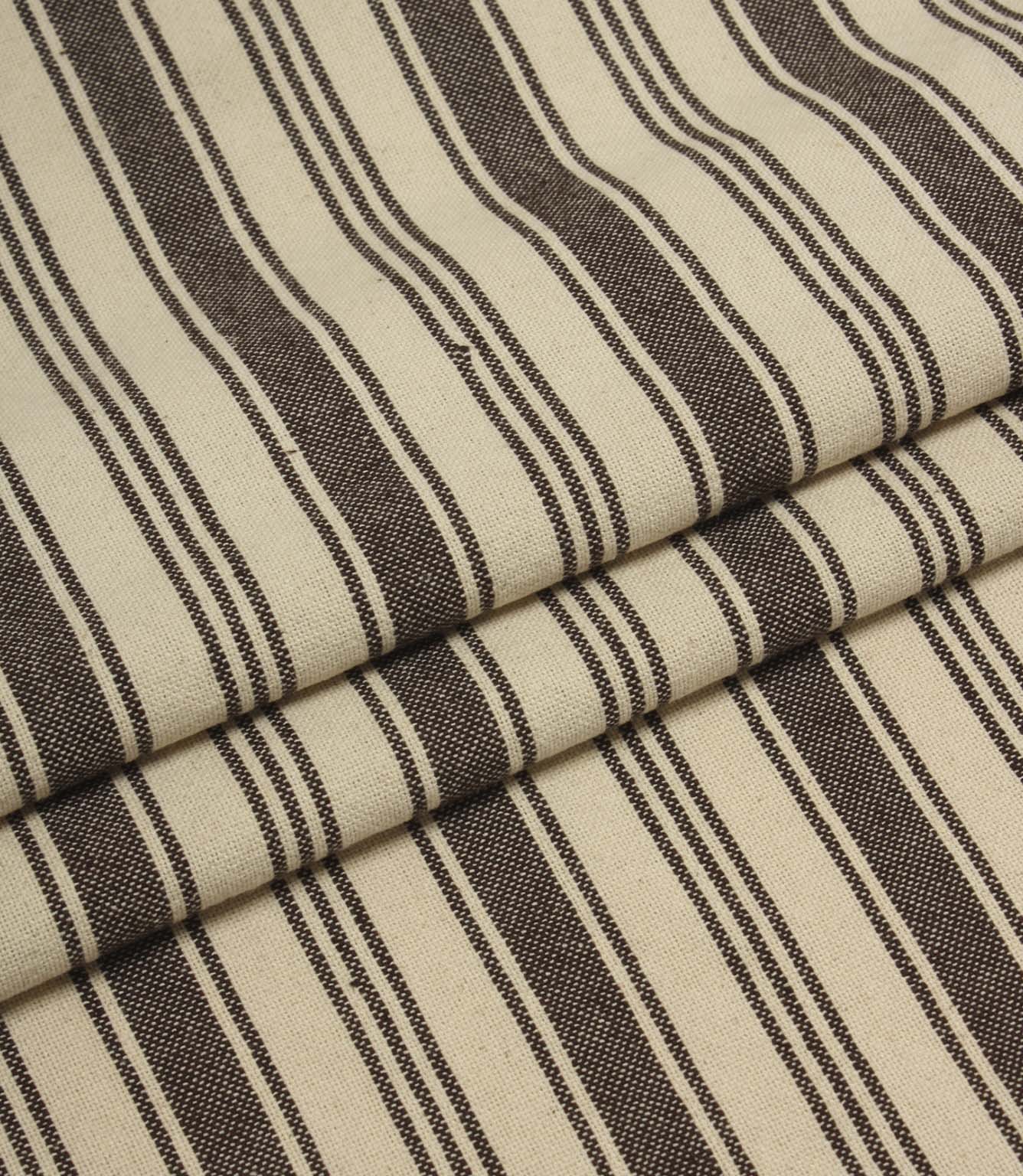 Folded cream and brown striped upholstery fabric showing the repeating stripe pattern and soft woven texture.