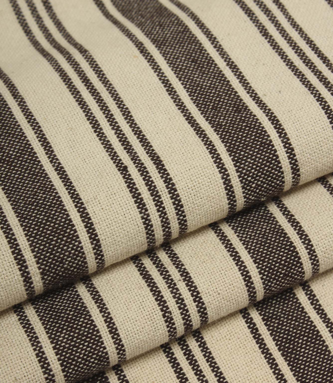 Detailed close-up of folded cream and dark brown striped fabric with contrasting stripe widths and textured weave.