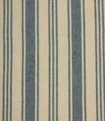 Close-up of blue striped upholstery fabric with textured weave detail, combining bold denim-blue stripes and narrow pinstripes on a natural cream background.