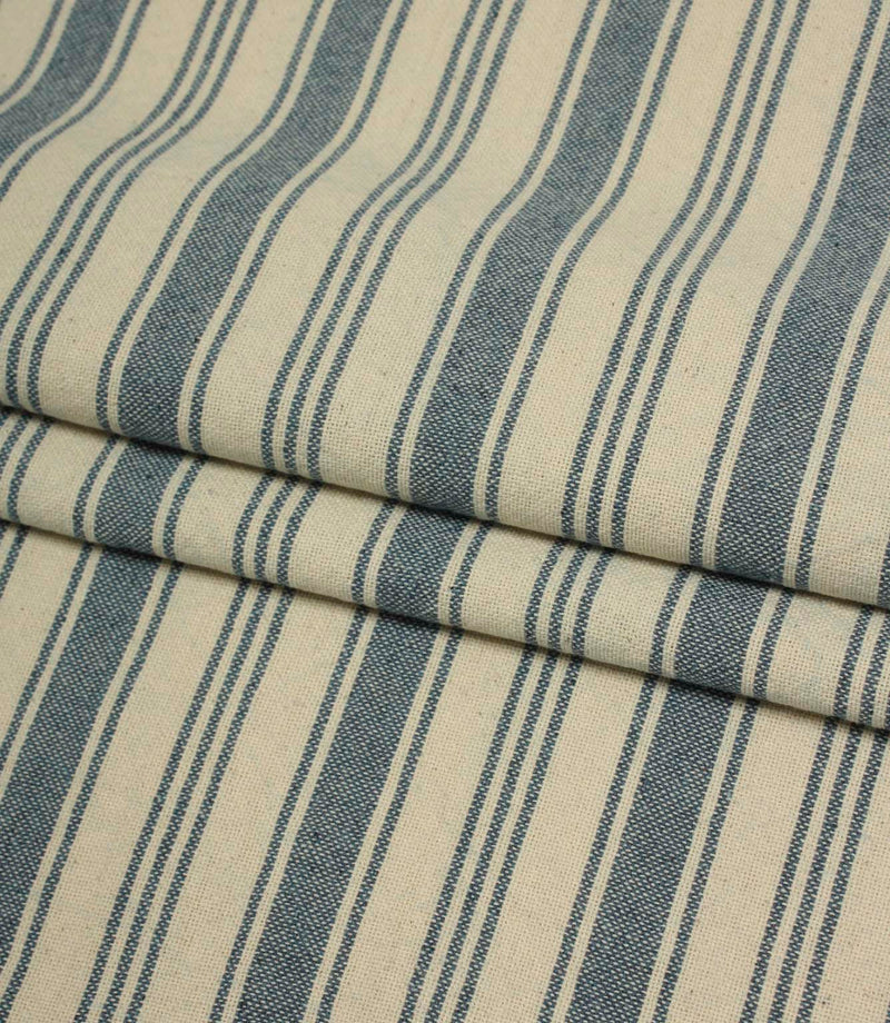 Folded blue and cream striped fabric showcasing the soft drape and woven texture of the classic ticking stripe pattern.