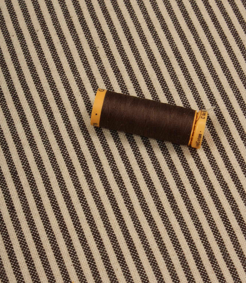 Brown striped upholstery fabric displayed with matching thread spool for colour coordination.