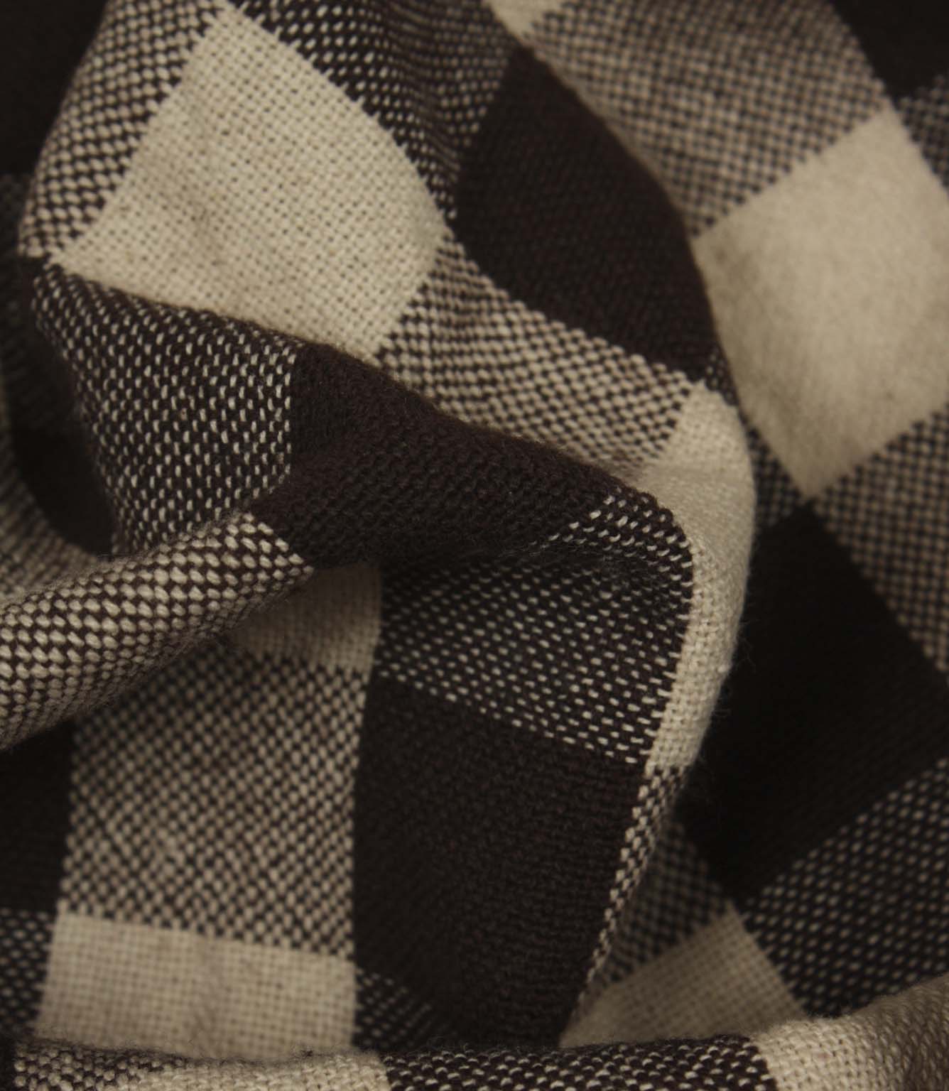 Detailed close-up of woven gingham fabric featuring bold brown and cream check squares.