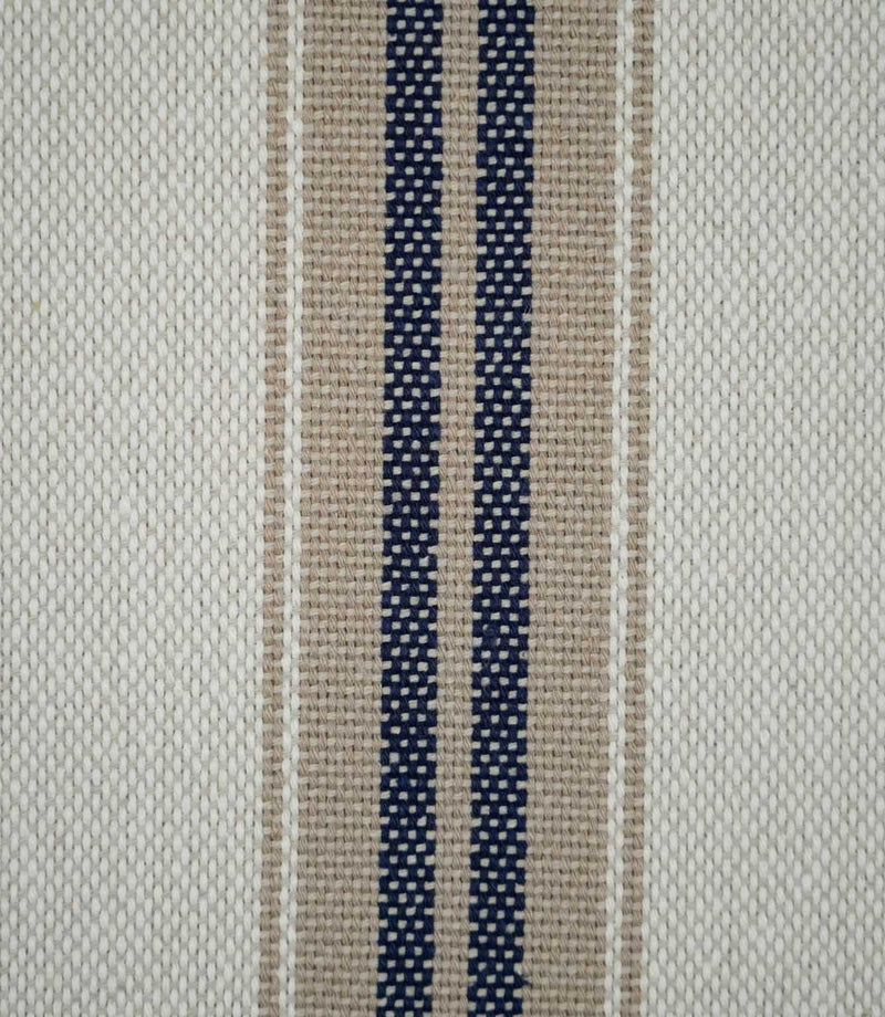 Close-up of Alma Stripe Marina fabric showing the textured woven construction with twin navy blue stripes, natural beige detailing and an off-white ground.
