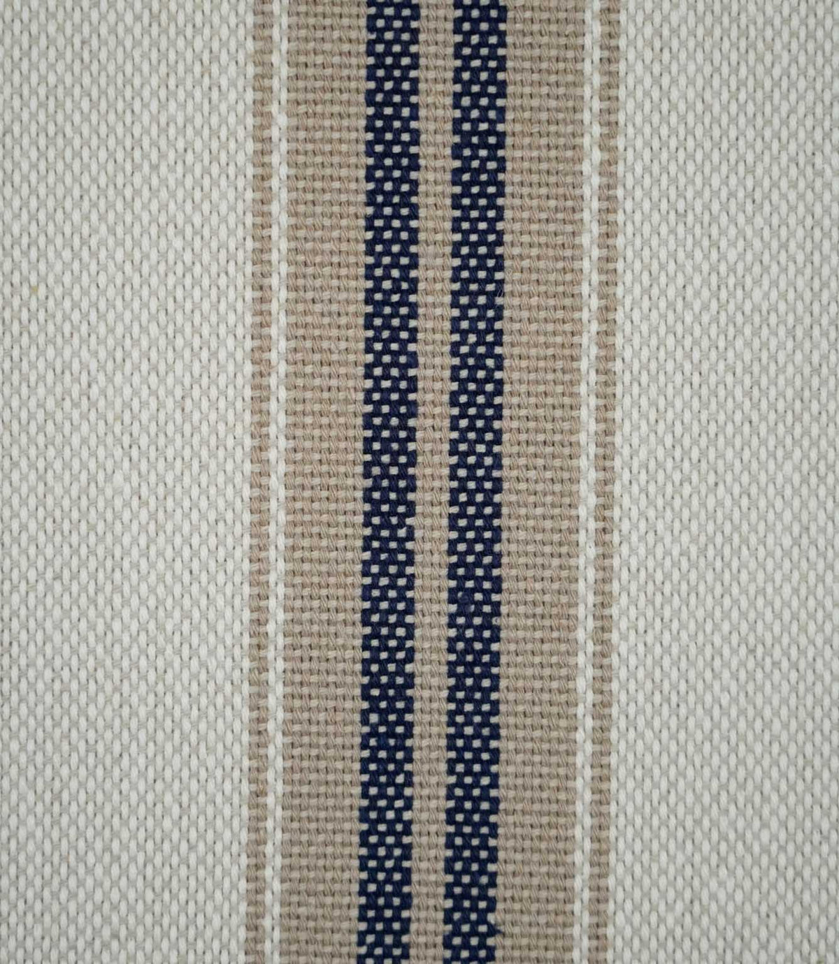 Close-up of Alma Stripe Marina fabric showing the textured woven construction with twin navy blue stripes, natural beige detailing and an off-white ground.