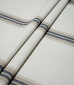 Alma Stripe Marina woven fabric arranged in soft folds, showing the widely spaced navy blue and beige stripe pattern across the off-white ground.