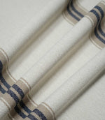 Close-up of Alma Stripe Marina fabric draped in soft folds, highlighting the substantial woven texture and repeating navy blue and natural beige stripes.