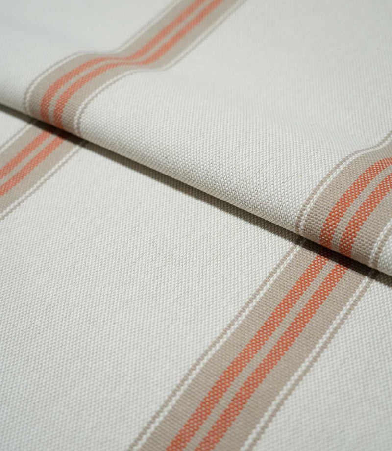 Folded Alma Stripe Terracotta fabric showing the off-white woven ground with repeating terracotta and natural beige stripes and a tactile textured finish.