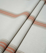 Alma Stripe Terracotta woven fabric arranged in soft folds, showing the repeating terracotta double stripe and natural beige detailing across the off-white ground.