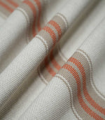 Macro close-up of Alma Stripe Terracotta fabric draped in soft folds, showing the textured off-white weave and terracotta double stripes within natural beige bands.