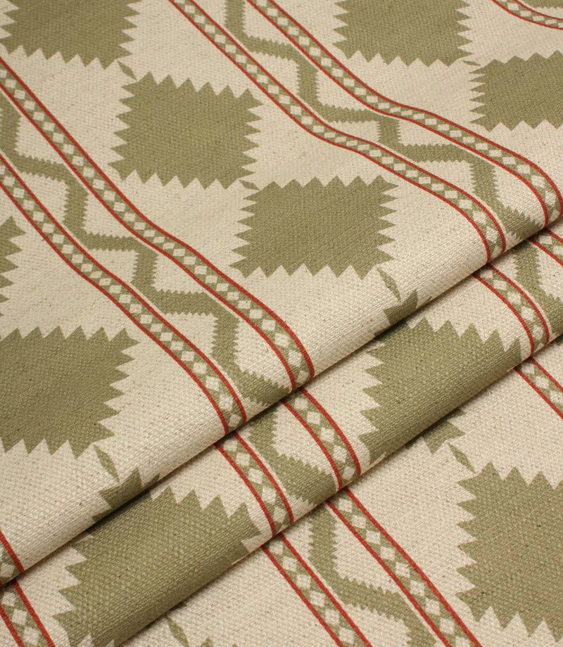 Folded sage green geometric fabric showcasing the structured drape and repeating tribal-style diamond pattern with red stripe accents.