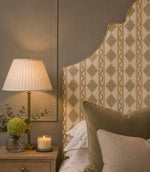 Arlo Geo Mushroom fabric upholstered headboard featuring a soft neutral geometric floral stripe pattern on a natural background with golden piping, styled with olive velvet cushions and a bedside table.