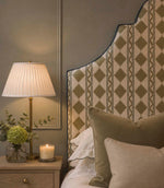 Arlo Geo Olive fabric upholstered headboard featuring repeating olive geometric motifs and striped detailing on a natural background, finished with contrasting blue piping and styled with olive and neutral cushions.