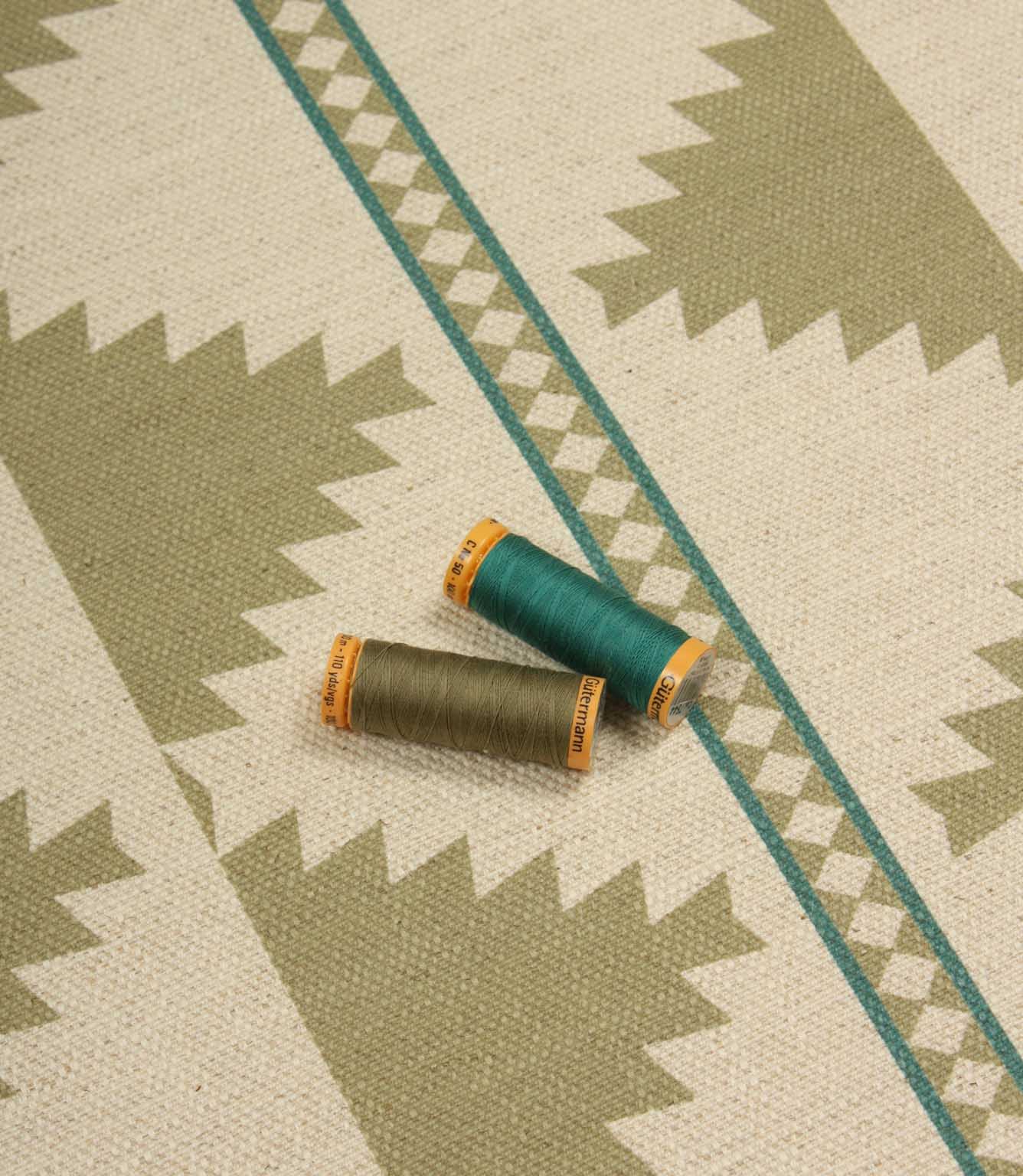 Three spools of thread on a fabric with geometric pattern