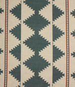 Cream woven fabric with a bold geometric tribal-inspired pattern in muted teal and rust red, featuring repeating diamond motifs and decorative border stripes.