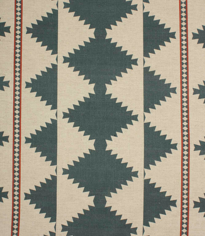 Cream woven fabric with a bold geometric tribal-inspired pattern in muted teal and rust red, featuring repeating diamond motifs and decorative border stripes.