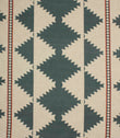 Cream woven fabric with a bold geometric tribal-inspired pattern in muted teal and rust red, featuring repeating diamond motifs and decorative border stripes.
