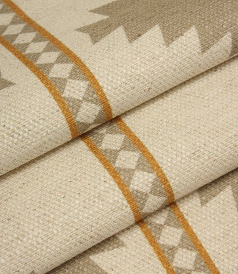Draped geometric upholstery fabric with oversized taupe diamond motifs and warm ochre accents on a soft natural cream background.
