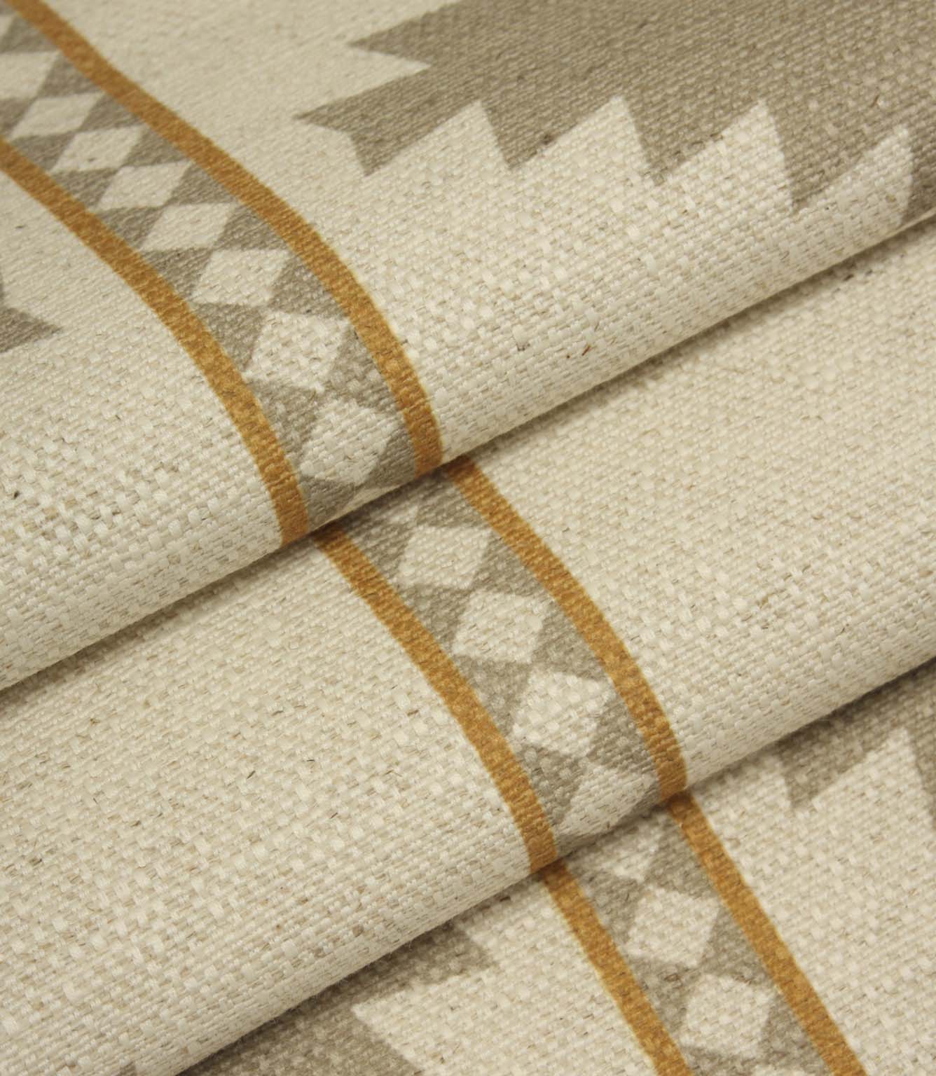 Draped geometric upholstery fabric with oversized taupe diamond motifs and warm ochre accents on a soft natural cream background.