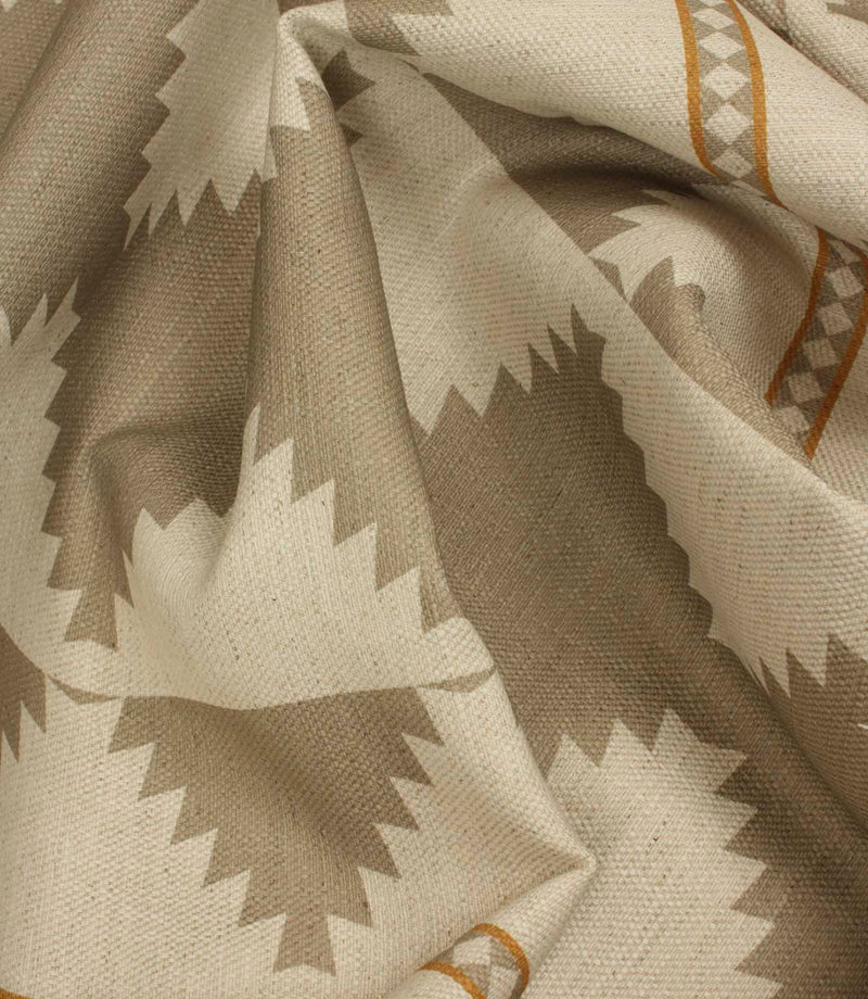 Macro close-up of woven cream fabric highlighting the textured weave, taupe geometric border pattern, and warm ochre accent stripes.