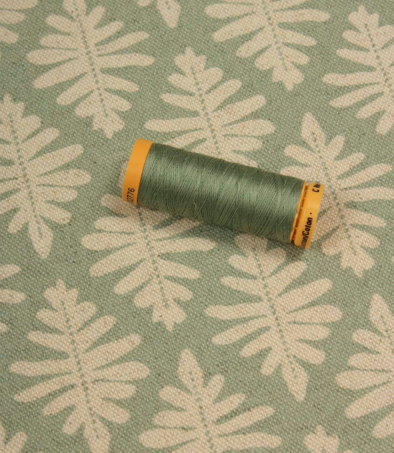 Ashleaf Dill fabric with a coordinating green thread spool highlighting the fabric’s colour and pattern.