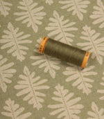 Detailed view of Ashleaf Lemon Grass upholstery fabric with matching thread spool for colour reference and scale.