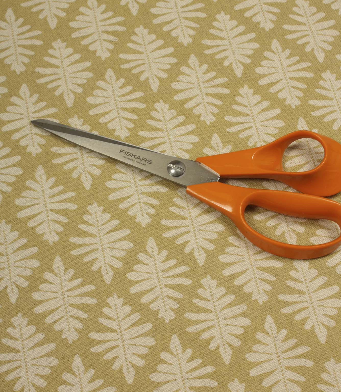 Ashleaf Pesto fabric shown with dressmaking scissors, illustrating the fabric's suitability for soft furnishing and craft projects.