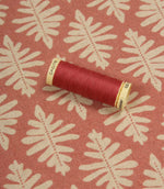 Ashleaf Raspberry fabric displayed with a matching raspberry thread spool, showcasing colour coordination and pattern detail.