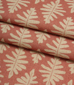 Folded Ashleaf Raspberry woven fabric showing the texture, depth and scale of the contemporary leaf design.