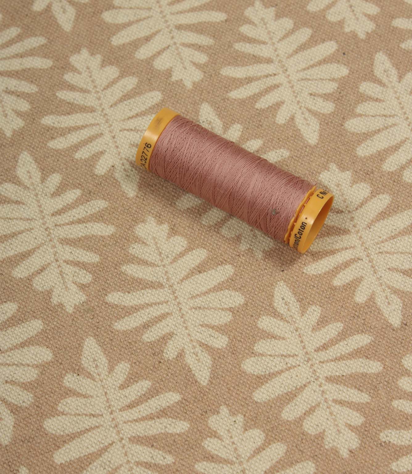 Ashleaf Tuskan Pink fabric with a coordinating pink thread spool, highlighting colour matching and pattern detail.