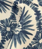 Draped Atlantic Flower outdoor upholstery fabric showing oversized blue floral motifs with soft painterly detailing on a natural ivory background.