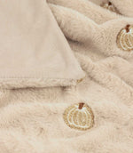 Close-up of the natural cream Autumn Pumpkins faux fur throw showing the plush pile, smooth cream reverse and detailed beige, white and brown embroidered pumpkin motif.