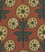 Close-up of Autumn Sunflower foliage outdoor fabric with decorative sunflower motifs in muted gold and forest green against a terracotta backdrop.

