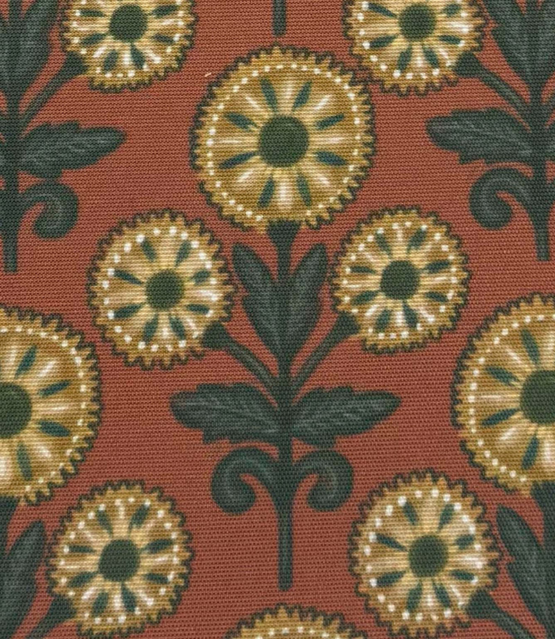 Close-up of Autumn Sunflower foliage outdoor fabric with decorative sunflower motifs in muted gold and forest green against a terracotta backdrop.

