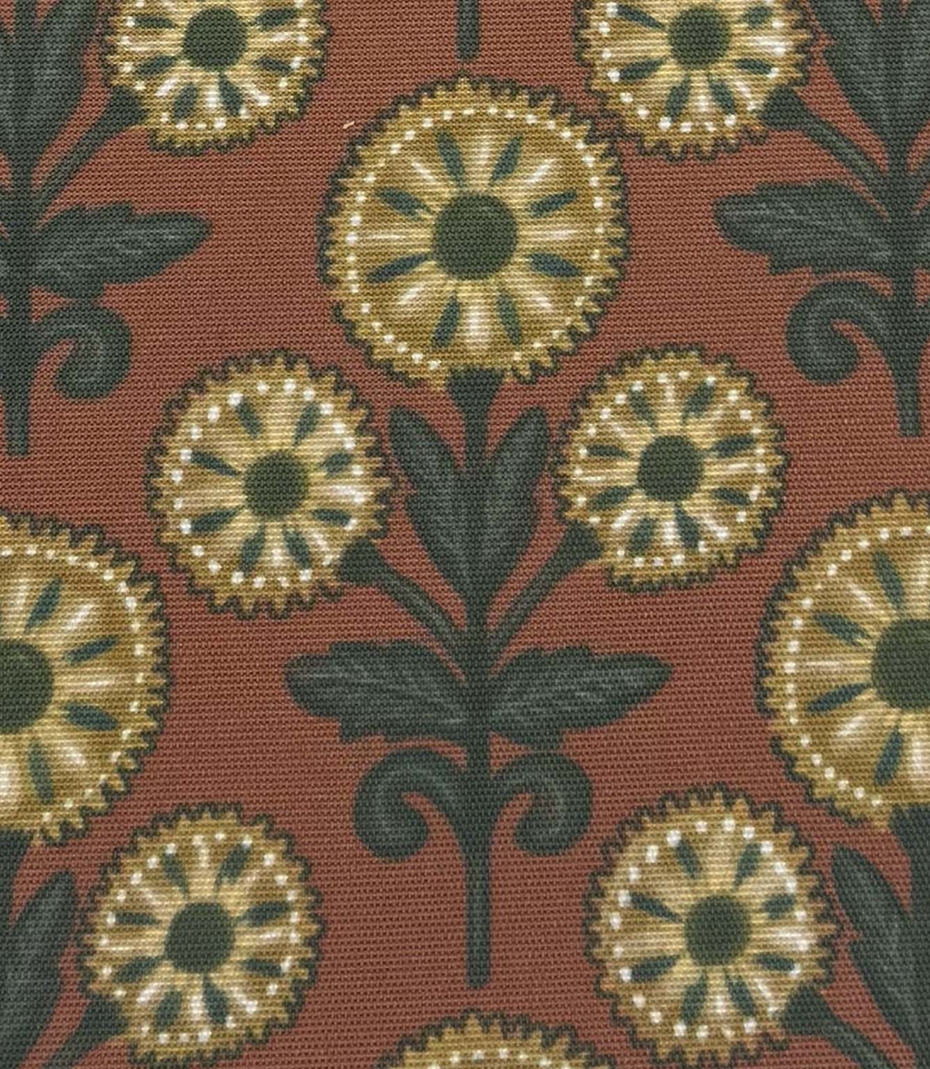 Close-up of Autumn Sunflower foliage outdoor fabric with decorative sunflower motifs in muted gold and forest green against a terracotta backdrop.

