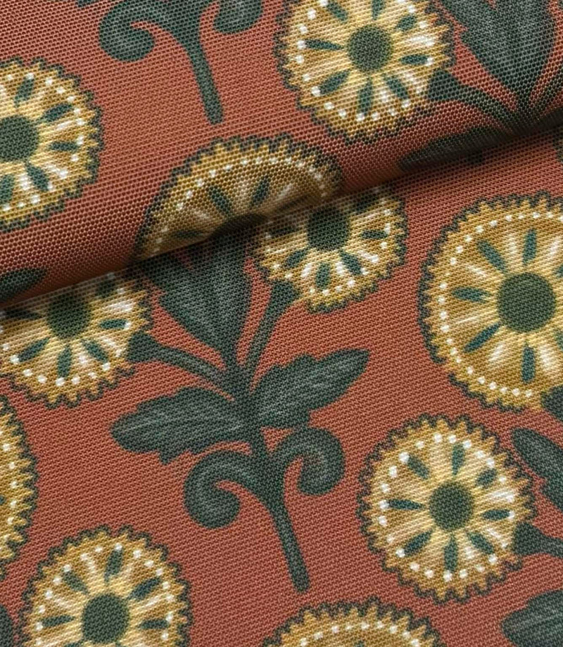 Folded Autumn Sunflower outdoor fabric featuring ochre floral motifs with dark green foliage on a terracotta background.